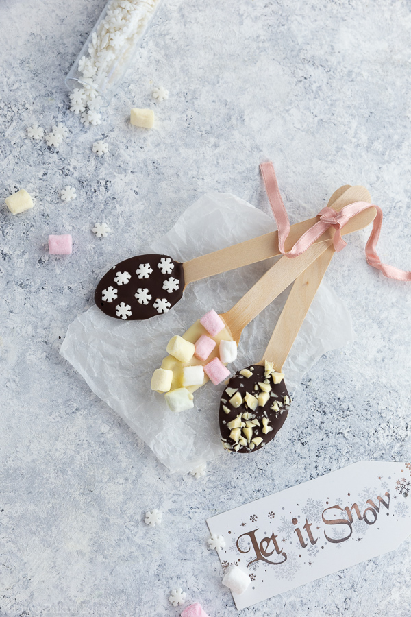 Chocolate spoons garnished with snowflake sprinkles, marshmallows and chocolate sprinkles.