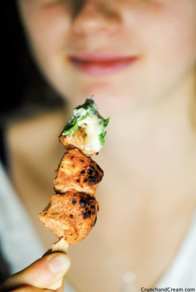 a woman about to eat a grilled taco chicken skewer