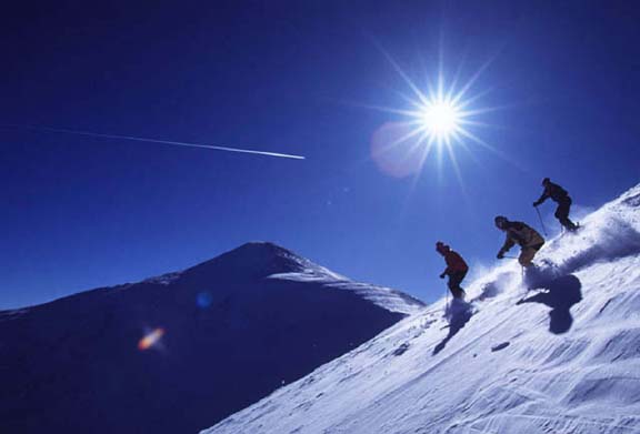 عکس های اسکی بازان در شیب سفید، با آسمان آبی تیره و خورشید سفید