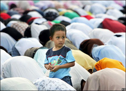 A young boy stands among worshippers as thousands of Filipino Muslims bow in prayer to celebrate Eid