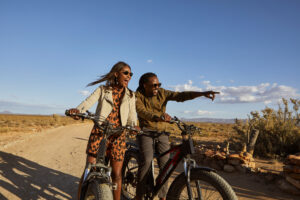 man and woman riding on motorcycle through desert