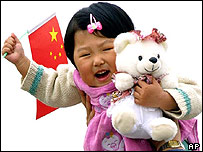 A child carries a toy bear and a flag on Beijing's Tiananmen Square