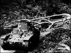 Two tanks one behind one in front of fallen tree